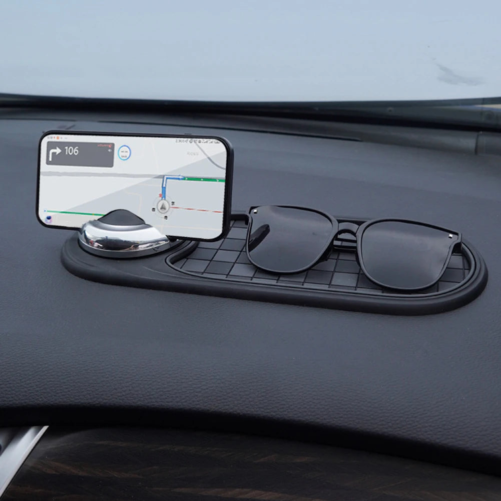 Car dashboard organizer with phone holder, sunglasses, and small round object.