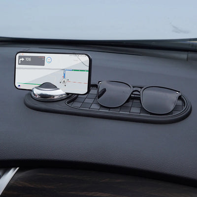 Car dashboard organizer with phone holder, sunglasses, and small round object.