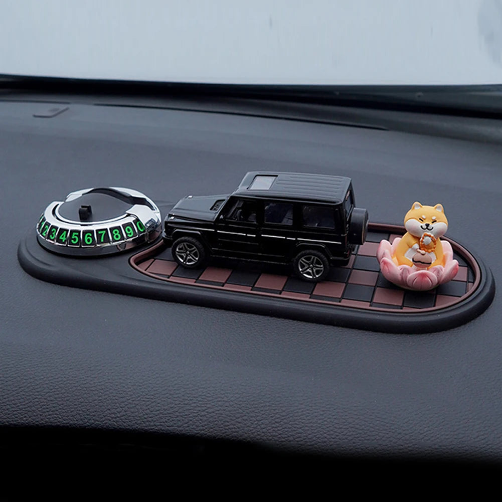 Decorative items on a car dashboard including a small car model, a dog figurine, and a circular device with numbers.
