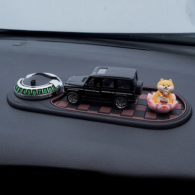 Decorative items on a car dashboard including a small car model, a dog figurine, and a circular device with numbers.